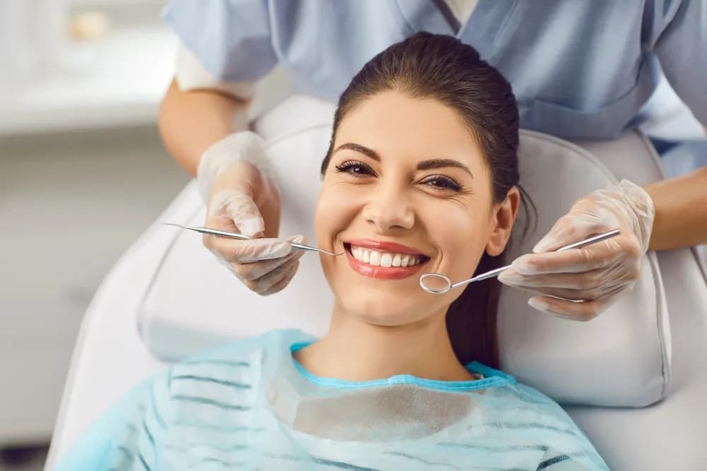 Patient receiving dental care while smiling, highlighting importance of aftercare for E.max veneers.